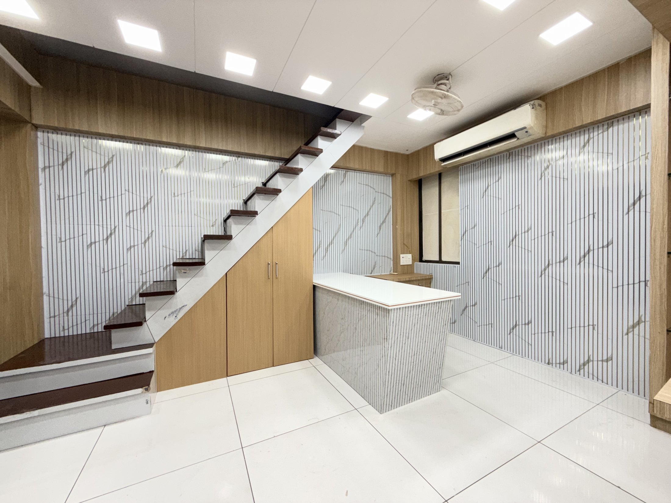 Commercial reception designed by Gharva Studio with a fluted marble desk, oak-panelled walls and an open timber staircase